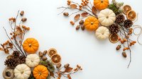 Autumn harvest decoration with orange and white pumpkins, pine cones, dried orange slices, acorns and branches on white background for seasonal design.