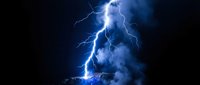 Powerful lightning bolt striking during intense thunderstorm with bright blue electrical discharge and smoke clouds against dark night sky for weather and nature projects.