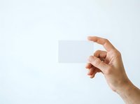 Male hand holding blank white card against neutral background, suitable for business cards, gift cards, promotional materials, and corporate branding presentations.