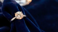 Elegant diamond solitaire engagement ring with brilliant cut stone in gold setting on luxurious navy blue velvet jewelry box for wedding proposal.