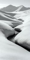 Meandering stream flows through snow-covered mountain landscape with pristine white drifts and peaks creating dramatic curves and shadows in monochromatic winter scene.