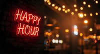 Red neon happy hour sign glowing on brick wall with warm string lights creating cozy bar atmosphere for nightlife entertainment and social gathering.