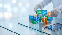 Hands in white gloves arranging colorful transparent cubes on glass surface with smartphone nearby, representing data organization, business strategy, and digital technology solutions.