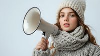Young woman with knitted hat and scarf holding megaphone for announcement or protest communication on white background isolated for design use.