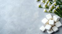 White fluffy marshmallows and fresh daisies arranged on light gray concrete background with copy space for text, flat lay composition for food styling.