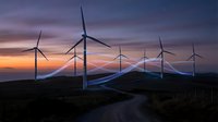 Wind turbines on hillside at sunset generating renewable energy with dramatic purple and orange sky creating sustainable power landscape.