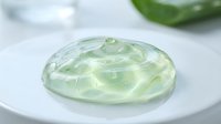 Transparent green gel sphere with liquid texture on white plate, suitable for cosmetics, skincare, beauty product mockups, and scientific presentations.