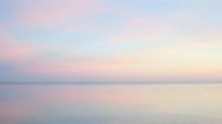 Serene dawn or dusk seascape with soft pastel pink, purple, and blue hues reflecting across calm water, creating a tranquil, minimalist coastal scene.