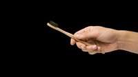 Caucasian hand holding a bamboo toothbrush with charcoal bristles, isolated on transparent background, ready for eco, dental, or hygiene clipart and print on demand designs.
