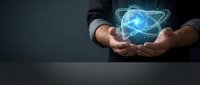 Businessman hands holding glowing atomic structure hologram with orbiting electrons on dark background for technology and science concepts.