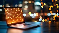 Modern laptop with glowing screen against blurred bokeh city lights background, creating magical evening atmosphere for business or holiday concept.