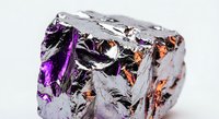 Metallic foil crumpled material with purple and orange reflective surfaces creating abstract textured background for modern design projects.