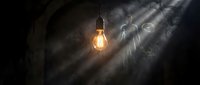Glowing vintage light bulb hanging in dark dusty space with dramatic rays of light, symbolizing ideas, innovation, and inspiration for creative concepts.