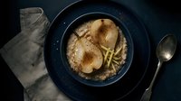 Overhead view of pan-seared chicken breast with golden fries served in dark bowl on black surface with linen napkin and spoon, ready for dining or restaurant menu photography.