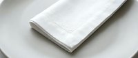 White linen napkin folded on ceramic plate, isolated on white background, ready for dining, hospitality, and tableware design projects.