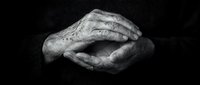 Elderly wrinkled hands clasped together in black and white, showing age, wisdom, and life experience through detailed skin texture and veins.