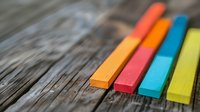 Vibrant colorful chalk pastels arranged in diagonal line on rustic wooden surface with selective focus and shallow depth of field creating artistic composition.