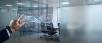 Business professional interacting with futuristic holographic interface displaying data analytics and workflow diagrams in modern office environment.
