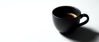 Black ceramic cup filled with hot coffee or tea on white background, isolated for beverage, cafe, and morning routine design projects.