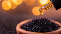 Golden drop of oil falling onto black caviar in traditional clay bowl against blurred warm bokeh background, luxury gourmet food concept.