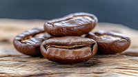 Macro shot of roasted coffee beans with rich brown color and distinctive crack lines on rustic wooden surface, showing texture and natural patterns in sharp detail.