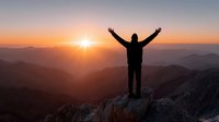 Silhouette of person with raised arms celebrating success on mountain peak at sunrise with golden sunlight and layered mountain ranges in background.