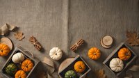 Autumn harvest flat lay with orange and white pumpkins, cinnamon sticks, wooden trays on burlap background for seasonal decoration and thanksgiving design.