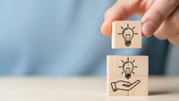 Hand placing wooden blocks with lightbulb icons representing creative ideas, innovation and business solution concepts for brainstorming sessions.
