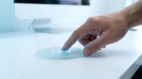 Male hand touching glowing futuristic holographic interface on white desk, digital fingerprint scan, biometric security technology concept.