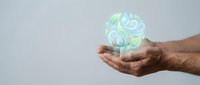 Male hands holding glowing green energy sphere with swirling patterns against gray background for wellness and healing concepts.