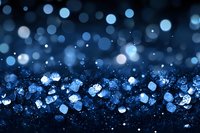 Sparkling blue glitter and bokeh lights scattered on dark background create magical festive atmosphere for holiday designs and celebrations.