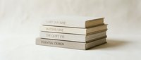 Stack of four neutral-toned design books with minimalist covers on white background for creative workspace and interior styling concepts.