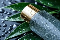 Luxury cosmetic bottle with water drops on dark background with green tropical leaves, wellness and spa concept for skincare advertising.