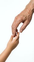 Elderly wrinkled hand reaching down to touch young smooth child hand on white background showing generational connection and family bond.