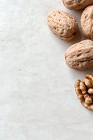 Whole and cracked walnuts on light textured background with copy space. Natural food photography for healthy eating and nutrition concepts.