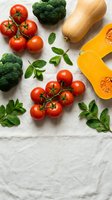 Fresh organic vegetables including ripe cherry tomatoes, broccoli, butternut squash and mint herbs arranged on white wooden background for healthy cooking.
