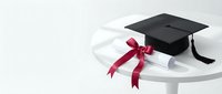 Black graduation cap with tassel and rolled diploma tied with red ribbon on white round table, academic achievement concept.