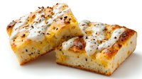 Homemade focaccia bread squares with herbs, cheese topping and golden crust, perfect for appetizers or accompanying Italian meals.