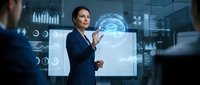 Professional businesswoman presenting AI brain hologram technology in modern corporate boardroom with digital analytics displays and data visualization.