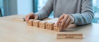 Professional woman arranging wooden blocks with emoji faces representing customer satisfaction journey feedback rating system in modern office.
