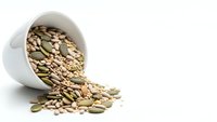Mixed seeds and nuts spilling from white ceramic bowl on clean background for healthy eating and nutrition concepts.