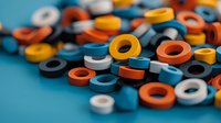Colorful industrial rubber washers and seals in orange, blue, white scattered on surface. Close-up macro photography with selective focus for engineering designs.