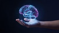 Glowing digital brain hologram floating above open palm against dark background representing artificial intelligence, neuroscience and mental health concepts.