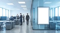 Modern office interior with blank digital display screen and business professionals in background discussing work in contemporary corporate workspace.