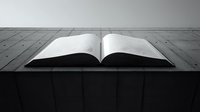Open book with blank pages on wooden surface in dramatic black and white lighting, creating minimalist composition for concepts of knowledge, storytelling and education.