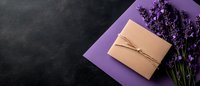 Kraft paper gift box tied with twine on purple background with fresh lavender flowers, dark stone backdrop. Minimalist composition with copy space.