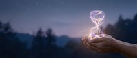 Hands holding glowing hourglass with light trails against twilight forest landscape, symbolizing time management and passing moments.