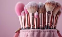 Professional makeup brushes set in pink holder against soft pink background, featuring fluffy powder and blending brushes with rose gold handles for cosmetic application.