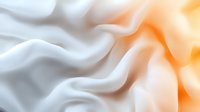 Soft white and peach colored fabric waves creating gentle flowing curves and folds with smooth silky texture and elegant abstract background pattern.