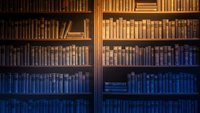 Vintage library bookshelf with old leather-bound books in warm golden and blue lighting creating cozy academic atmosphere for reading and study spaces.